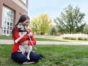 A girl hugs a husky dog outside